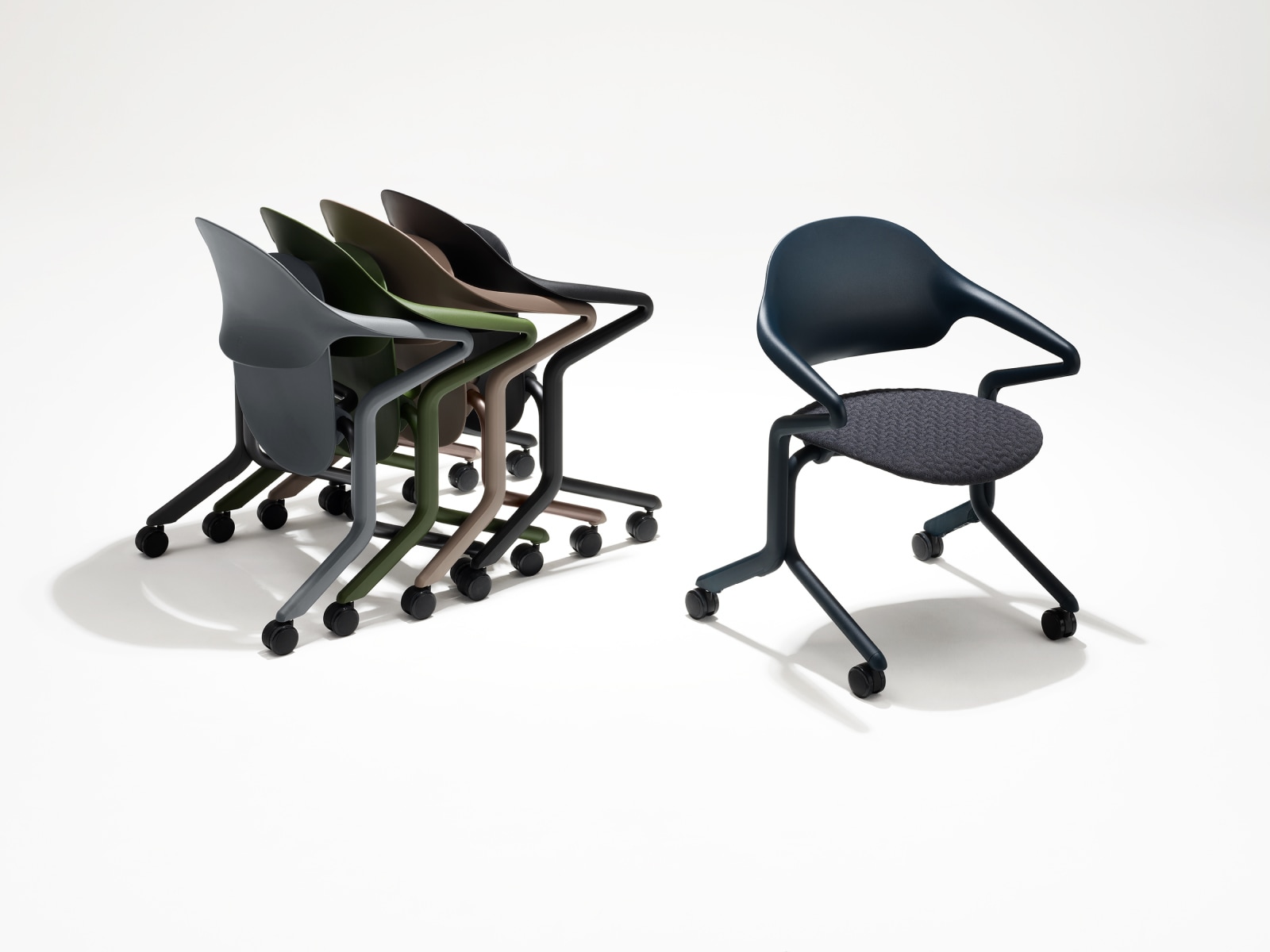Vier zusammengesteckte Fuld Stühle mit verschiedenen Farben und Oberflächen in einer Gruppe neben einem einzelnen Fuld Stuhl in Nightfall mit dem 3D-Knit Material.